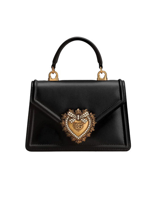 Black handbag with a decorative heart emblem on a light gray background